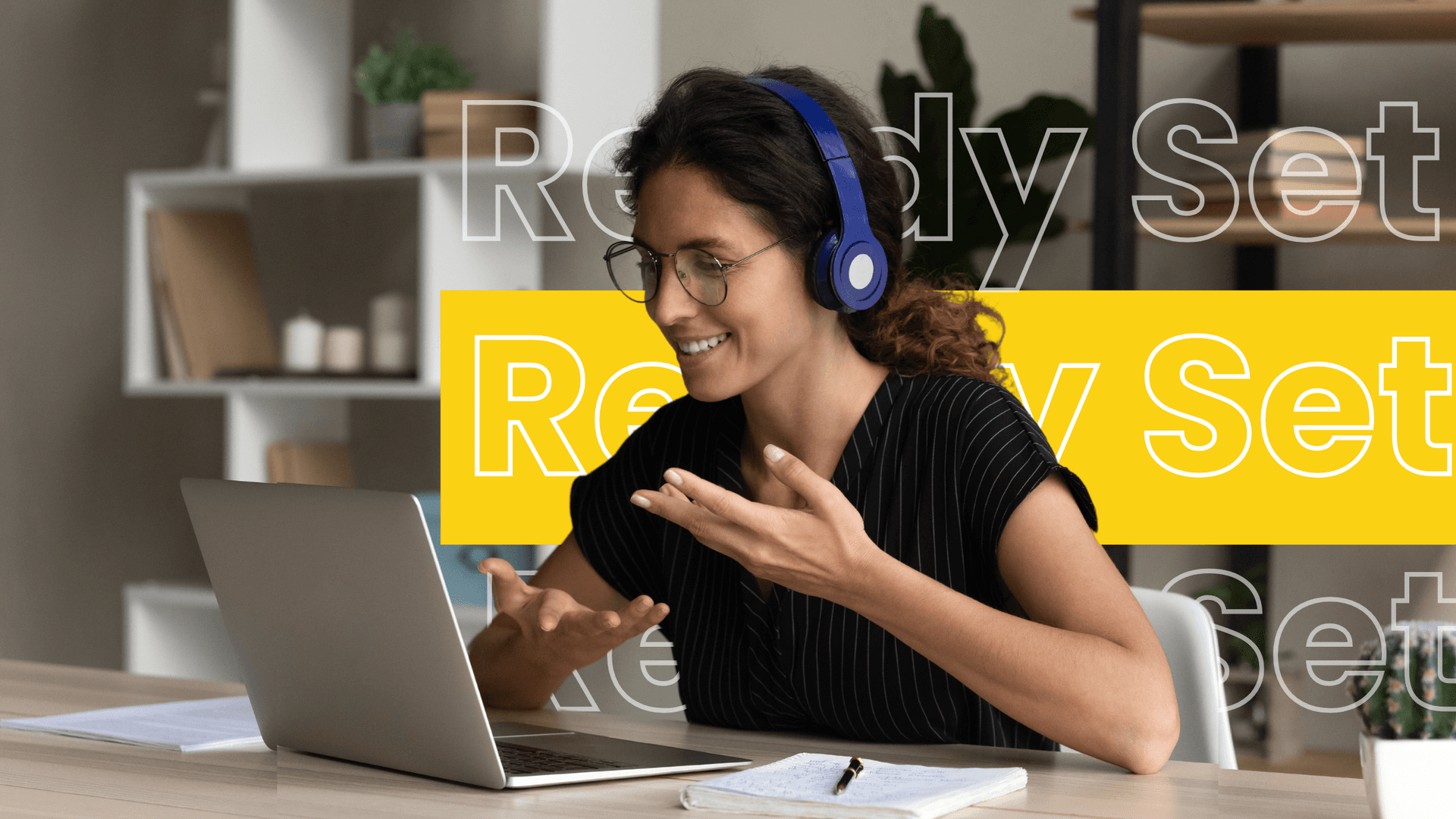 Pic of virtual assistant having a training session, wearing headphones and engaging in an online meeting, with a laptop and notepad on the desk.
