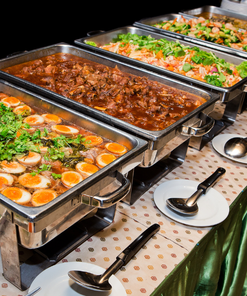 Catering buffet with various hot dishes and garnished items in chafing dishes