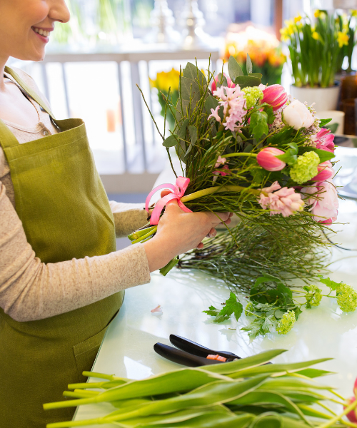 Florist arranging colorful spring bouquet with tulips and mixed flowers
