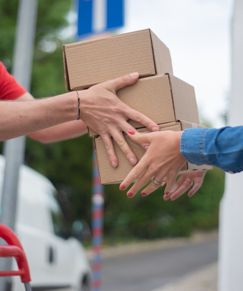 Hands exchanging cardboard delivery boxes outdoors